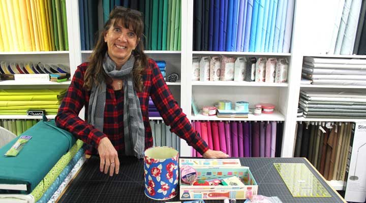 julia marquez of sewing arts stand in front of fabric supplies