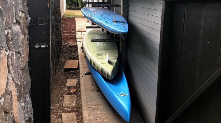 paddleboards stored on side of garage