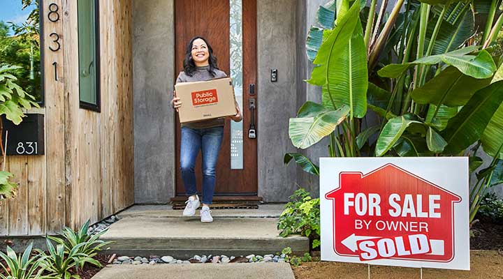 woman holding public storage moving boxes while moving out of her home