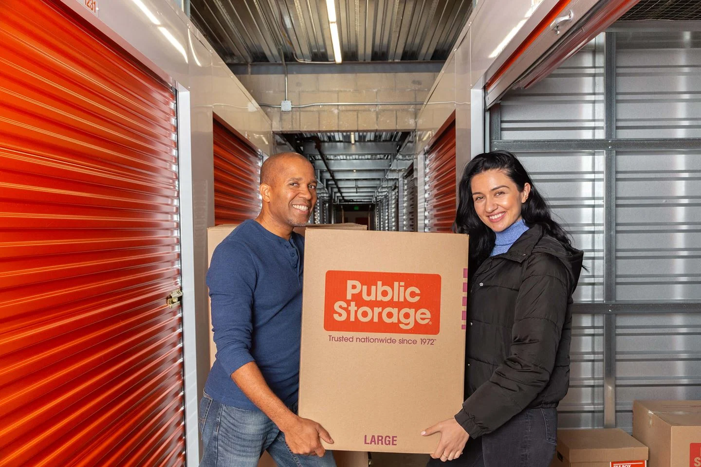 happy couple moving a storage box into their Public Storage unit